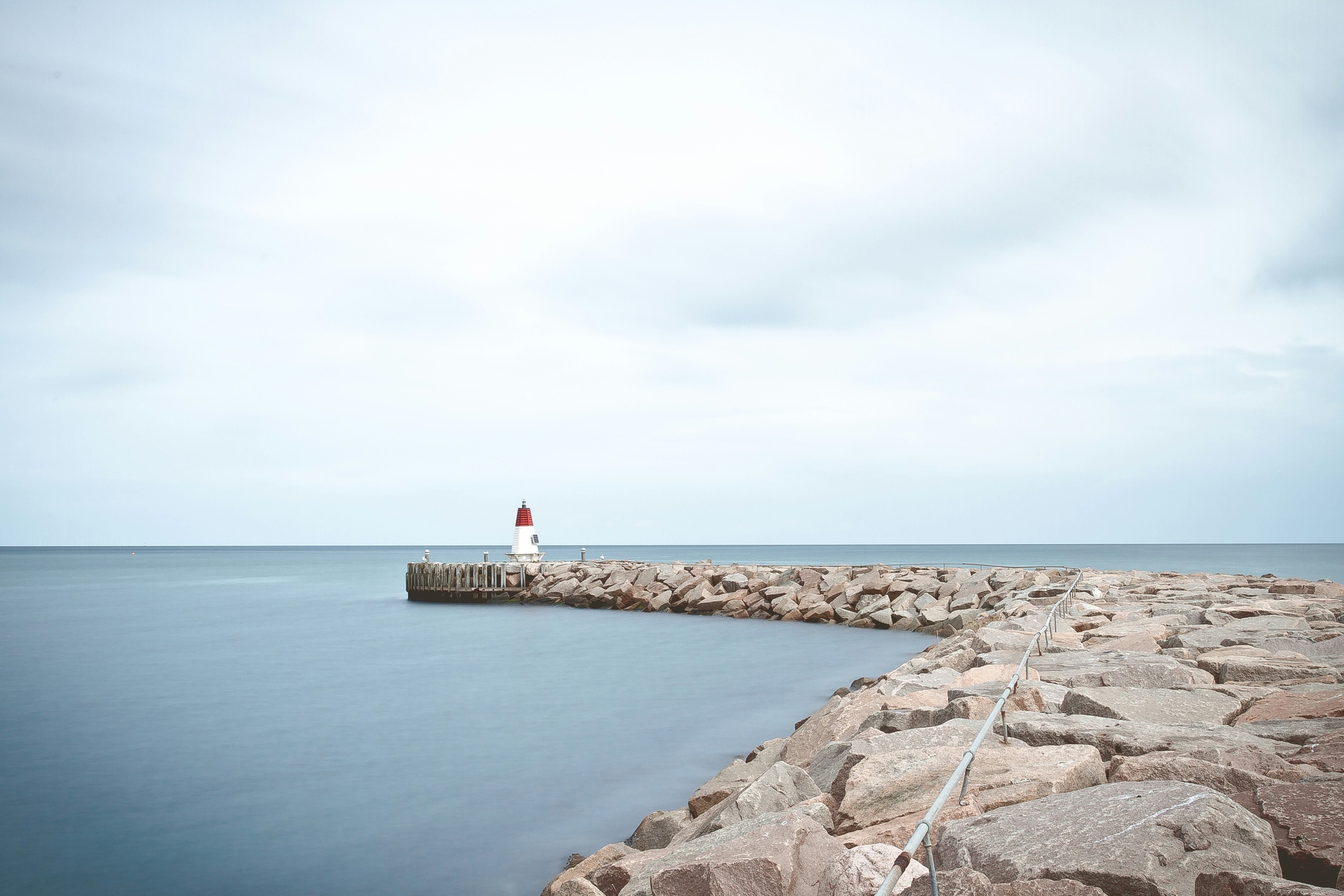 white and red lighthouse near sea at daytime